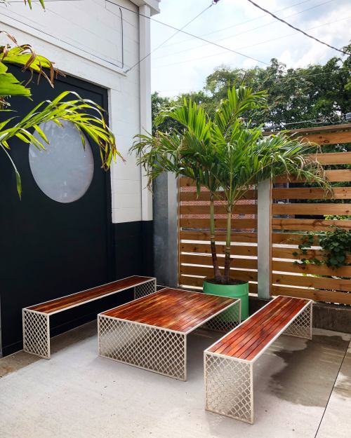 A cozy outdoor seating area featuring wooden benches and a potted palm tree against a modern backdrop.
