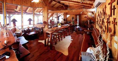 Cozy wooden interior with a large dining table, rustic decor, and cross wall art in a warm, inviting space.