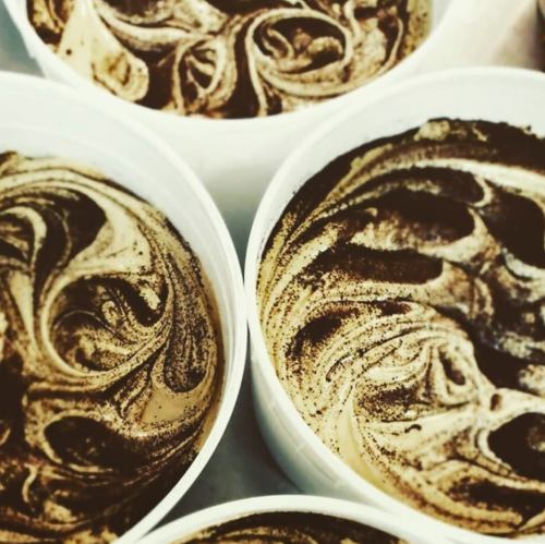 Four white containers filled with swirled, dark brown and cream-colored mixture, resembling coffee or dessert.