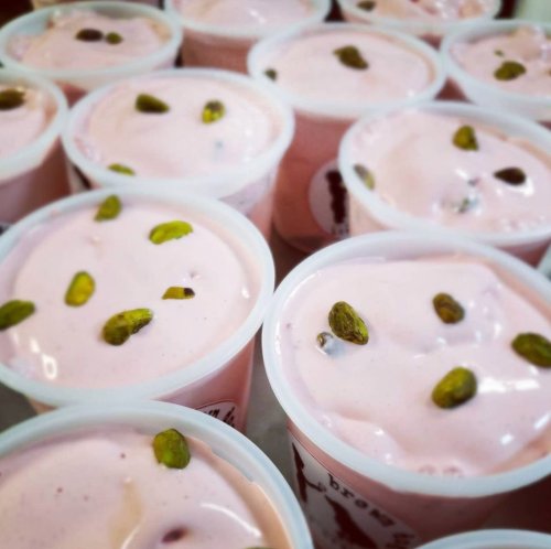 Close-up of multiple cups of pink dessert topped with green pistachios.