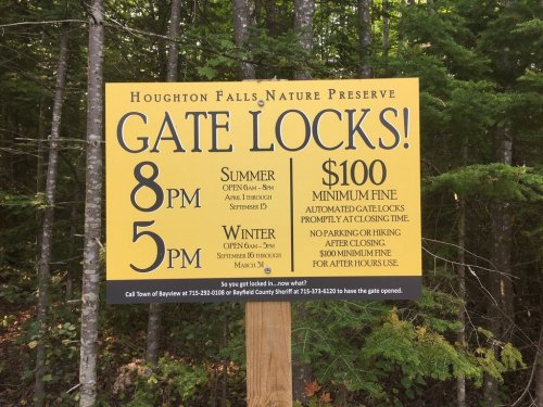 Sign at Houghton Falls Nature Preserve detailing gate lock hours and minimum fine for after-hours access.
