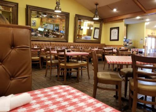 Interior of a restaurant featuring wooden tables with checkered tablecloths and a cozy, inviting atmosphere.