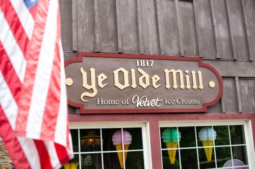 Sign for Ye Olde Mill, established in 1817, featuring "Home of Velvet Ice Creams" with colorful ice cream cone decorations.