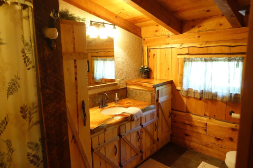 Cozy wooden bathroom with a rustic sink, mirror, and natural light from a small window.