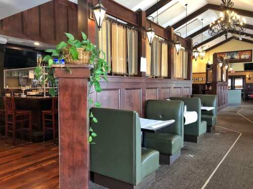 Interior of a restaurant featuring wooden booths, a bar area, and decorative lighting.