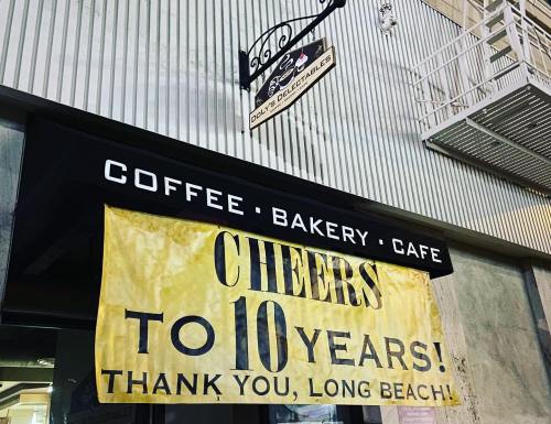 A sign celebrating 10 years of a coffee, bakery, and café in Long Beach, with a cheerful message.