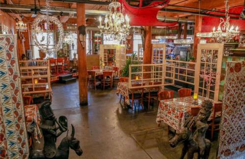 A vibrant restaurant interior with ornate chandeliers, patterned tables, and decorative sculptures.
