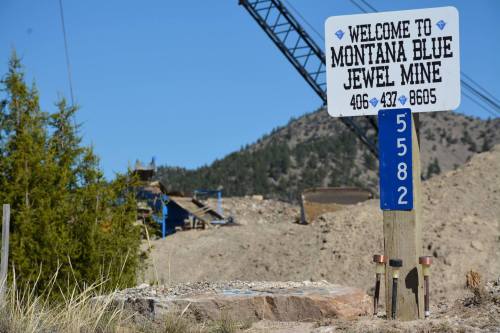 Sign welcoming visitors to Montana Blue Jewel Mine, with contact information and a mountainous background.