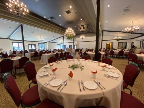 Elegant dining setup with round tables, white tablecloths, and decorative centerpieces in a spacious banquet hall.
