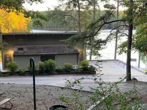 A small cabin by a lake surrounded by trees, with a deck and pathway leading to the water. Autumn foliage is visible.