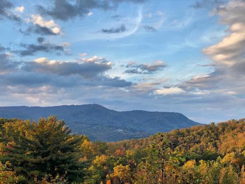 Scenic view of rolling mountains under a blue sky with clouds, surrounded by colorful autumn foliage.