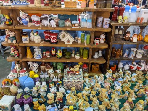 A colorful display of various ceramic figurines and collectibles on wooden shelves at a market.