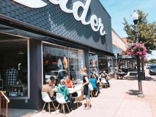 A bustling café with outdoor seating, people enjoying drinks, and a sunny day in a vibrant street setting.