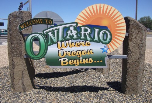 Welcome sign for Ontario, featuring the text "Where Oregon Begins" and a sun graphic in the background.