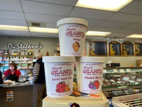 Three tubs of Mount Granita Italian Ice stacked on a counter, labeled Mango, Spiced Apple Cider, and Mixed Berry.