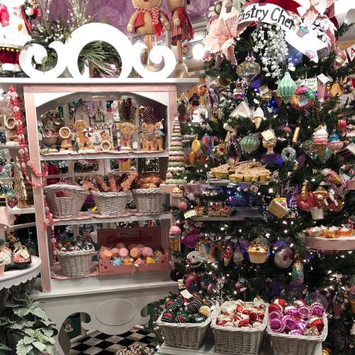 A festive display featuring a decorated Christmas tree and shelves filled with colorful ornaments and treats.