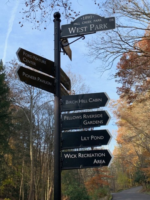 Signpost in a park with directional arrows pointing to various locations: Ford Nature Center, Pioneer Pavilion, and more.