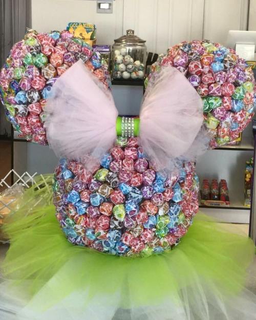 A colorful, oversized Minnie Mouse head made of wrapped candies, adorned with a pink bow and a green tutu.