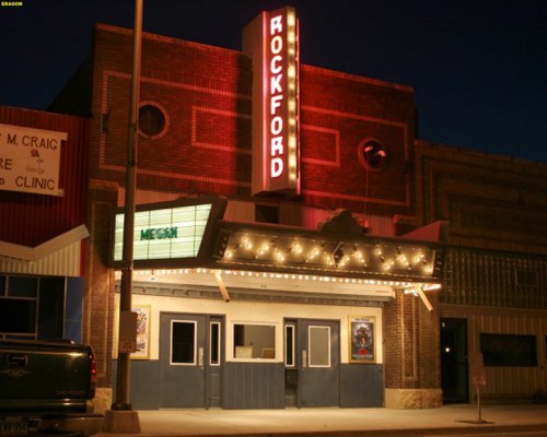 The illuminated facade of the Rockford theater at night, featuring a marquee and vintage architectural details.