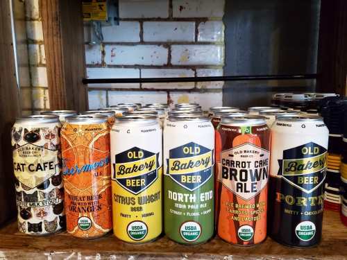 A display of various craft beer cans from Old Bakery Beer, featuring unique designs and flavors.