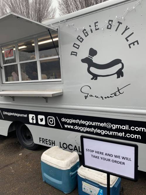 A food truck named "Doggie Style Gourmet" with a sign inviting customers to place their orders.