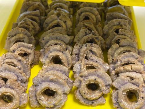 A yellow tray filled with neatly arranged circular slices of a grayish food item, possibly a type of snack or dessert.