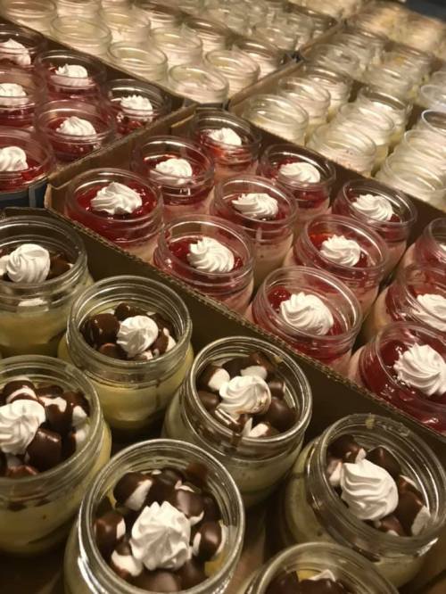 A variety of desserts in jars, featuring layers of cream, chocolate, and fruit, topped with whipped cream.