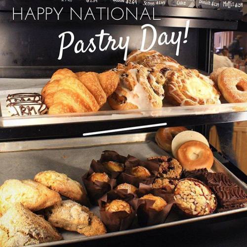 A display of various pastries, including croissants, danishes, and muffins, with a sign saying "Happy National Pastry Day!"