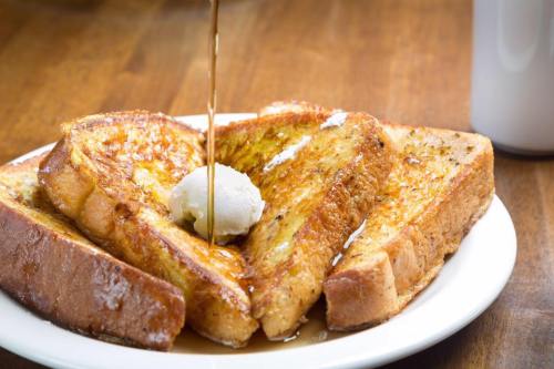 A plate of golden-brown French toast topped with a pat of butter and drizzled with syrup.