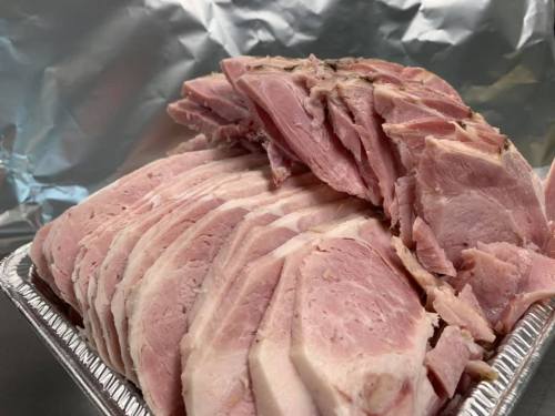 Sliced ham arranged in a tray, with a shiny foil background.