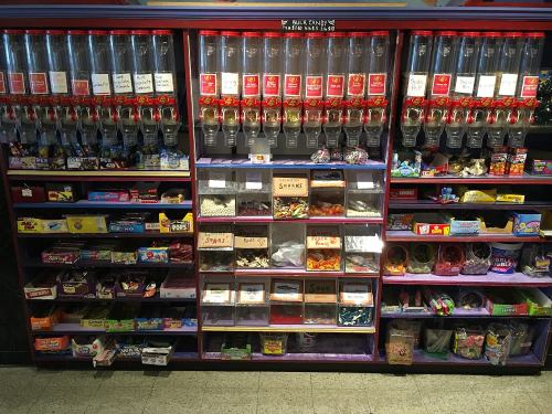 A colorful candy wall featuring various bulk candy dispensers and containers filled with assorted sweets and treats.