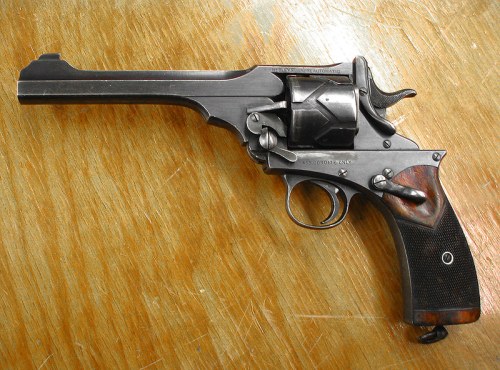 A vintage revolver with a wooden grip, resting on a wooden surface.