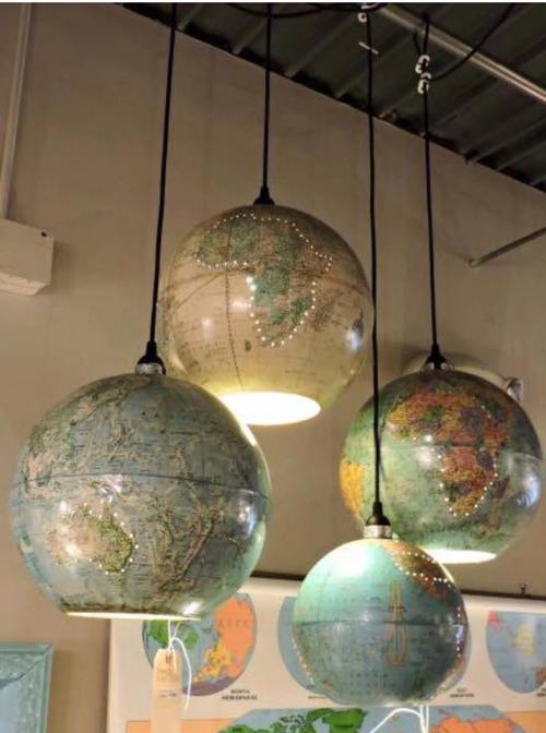 Four globe-shaped pendant lights hanging from the ceiling, featuring detailed world maps in various colors.