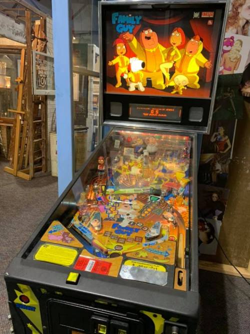 A colorful Family Guy pinball machine with vibrant artwork and characters displayed on the backboard.