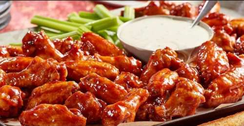 A platter of glazed chicken wings with celery sticks and a bowl of dipping sauce.