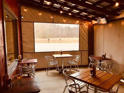 Cozy outdoor dining area with wooden tables, metal chairs, and warm lighting, surrounded by a scenic view.