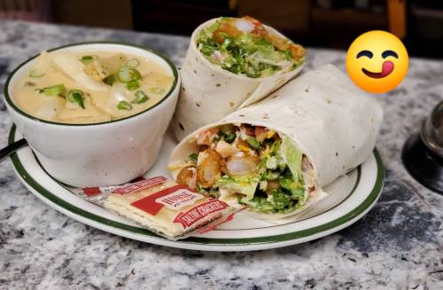 A plate with two wrapped burritos, a bowl of soup, and crackers, accompanied by a smiling emoji.