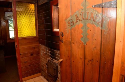 Wooden sauna door with decorative lettering, next to a brick wall and a window with textured glass. Cozy interior setting.