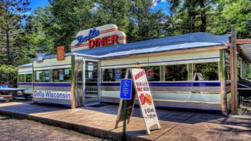 A retro diner in Delta, Wisconsin, featuring a shiny exterior and a sign advertising burgers and hours of operation.