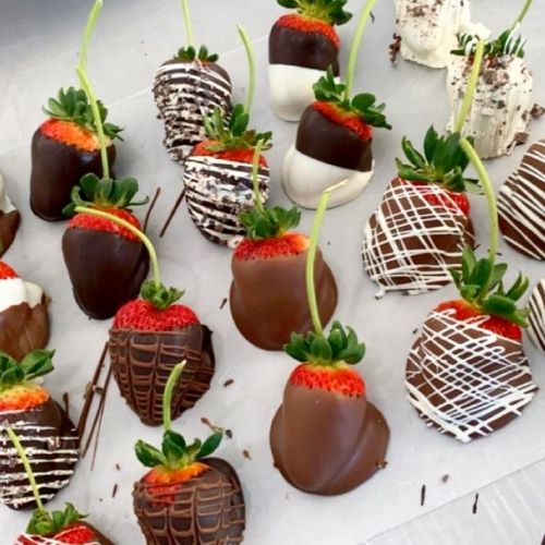 A variety of chocolate-covered strawberries, decorated with white and dark chocolate drizzles, arranged on a tray.