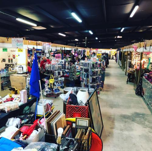 A bustling indoor market filled with various stalls selling items like masks, crafts, and home goods.