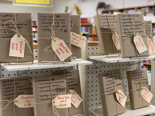 A display of wrapped books labeled "Blind Date with a Book," featuring tags with genres and themes in a bookstore.