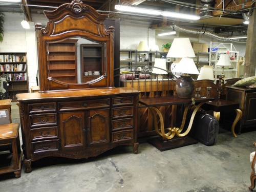 A collection of wooden furniture including a dresser, hutch, and tables, with lamps in a spacious indoor setting.