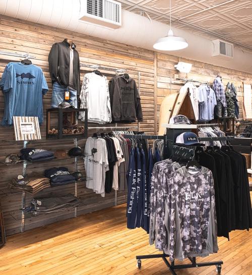 A retail display featuring various clothing items, including shirts and hoodies, arranged on wooden walls and racks.