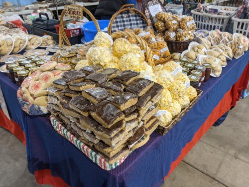 A colorful display of various baked goods, including cookies, popcorn, and treats, arranged on a table at a market.