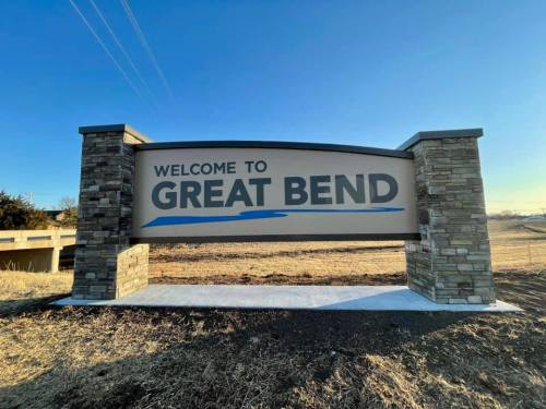 Sign welcoming visitors to Great Bend, featuring stone pillars and a clear blue sky in the background.