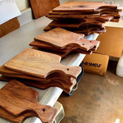 A stack of wooden cutting boards arranged on a countertop, showcasing their natural grain and shapes.