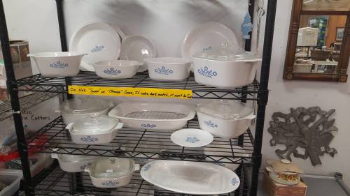 A display of white ceramic dishes with blue floral designs on a black metal shelf in a store.