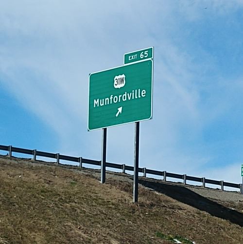 Green highway sign for Munfordville, indicating Exit 65, with an arrow pointing right.