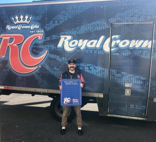 A person stands in front of a Royal Crown Cola truck, holding a sign that says "Welcome to Series Freeze."